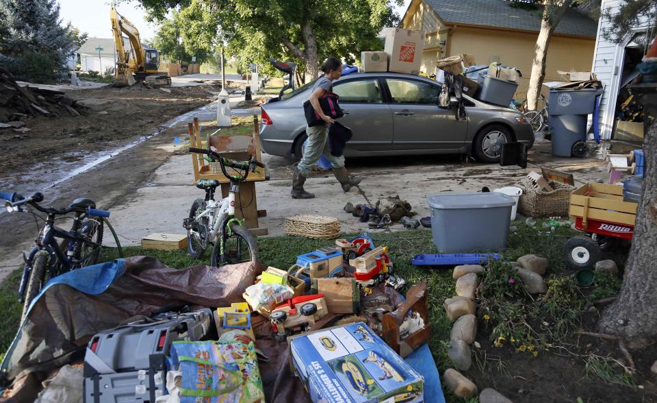 Shanda Roberson carries possessions back home as the contents from her flooded garage are seen lying in the yard to dry in Longmont, Colorado September 16, 2013. (REUTERS/Rick Wilking)