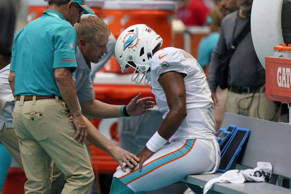 Team staff talk with Miami Dolphins quarterback Tua Tagovailoa (1) after he left the field injured during the first half of an NFL football game against the Buffalo Bills, Sunday, Sept. 19, 2021, in Miami Gardens, Fla. (AP Photo/Wilfredo Lee)