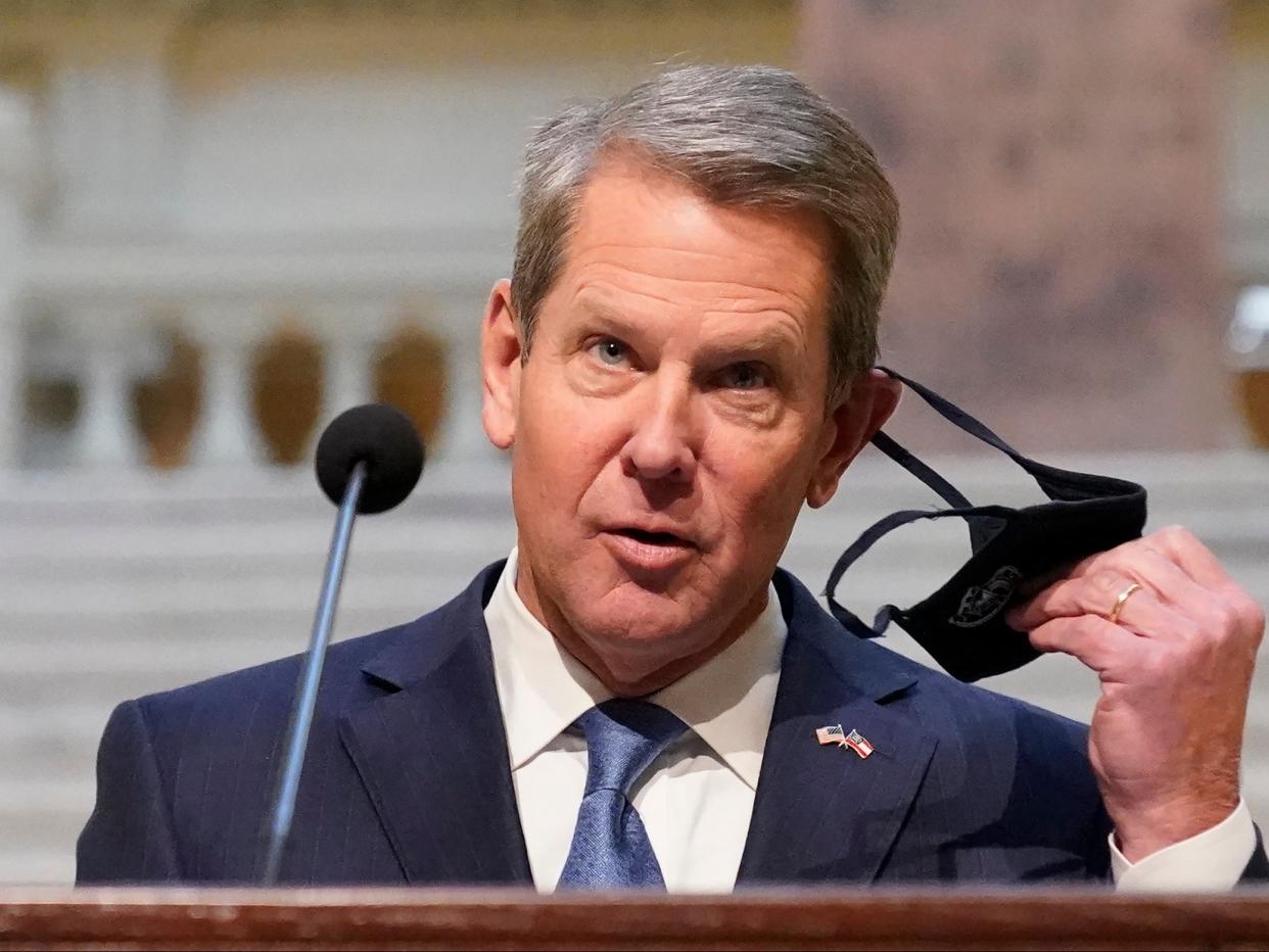 Georgia governor Brian Kemp removes his face covering before speaking to reporters during a Covid-19 update in the Capitol, Tuesday 8 December  2020, in Atlanta ((Associated Press))