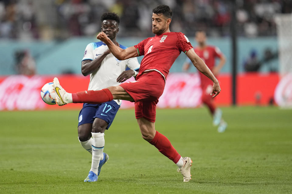 El iraní Morteza Pouraliganji (derecha) golpea la pelota delante de Bukayo Saka durante un juego del Grupo B del Mundial que enfrentó a Inglaterra e Irán en el estadio Jalifa Internacional en Doha, Qatar, el 21 de noviembre de 2022. (AP Foto/Abbie Parr)