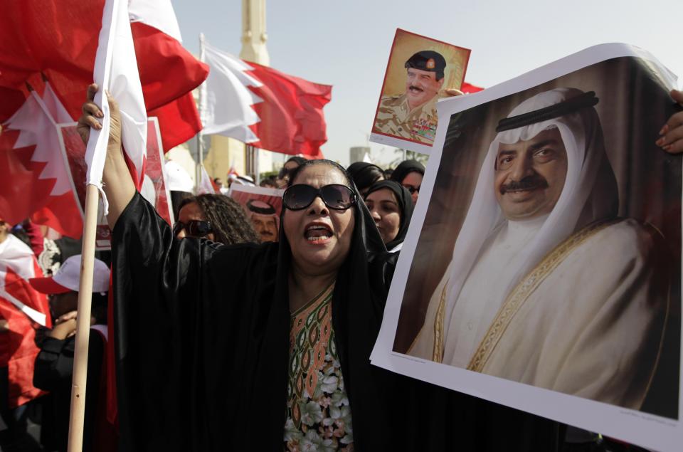 FILE - In this Feb. 18, 2011, file photo, a Bahraini pro-government protester shouts slogans as she holds a poster of Bahraini Prime Minister Khalifa bin Salman Al Khalifa during a march supporting the Bahraini leadership in Manama, Bahrain. Prince Khalifa, one of the world’s longest-serving prime ministers who led his island nation’s government for decades and survived the 2011 Arab Spring protests that demanded his ouster over corruption allegations, died on Wednesday, Nov. 11, 2020. He was 84. (AP Photo/Hassan Ammar, File)