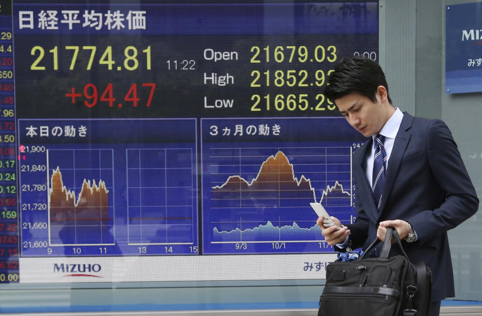 A man walks by an electronic stock board of a securities firm in Tokyo, Monday, Nov. 19, 2018. Asian shares were mostly higher Monday after a buying spree on Wall Street kept up investor optimism into a new week, despite continuing worries about trade tensions. (AP Photo/Koji Sasahara)