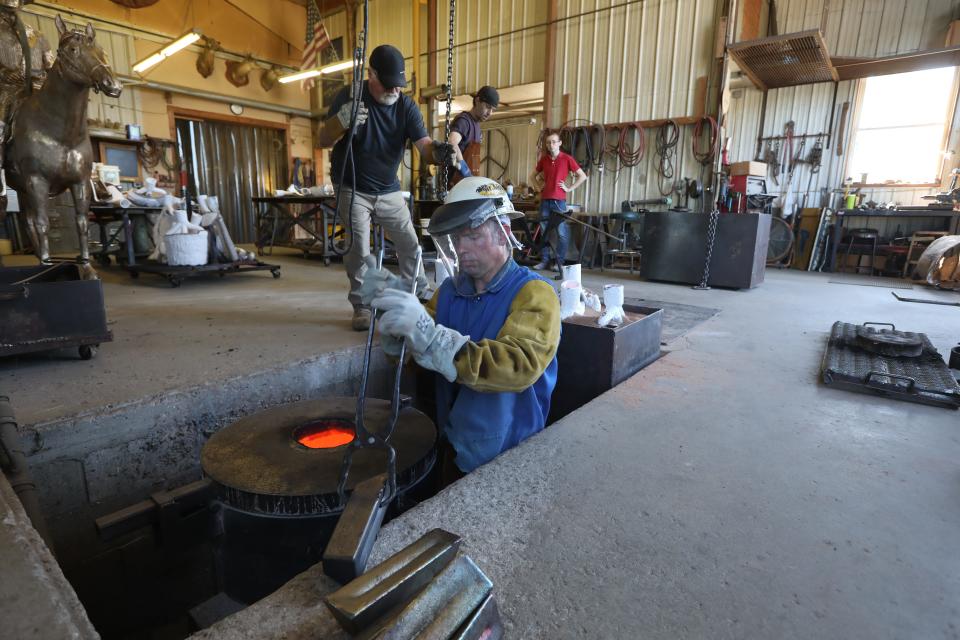 Josh Becker puts bronze ingots into a furnace at Coopermill Bronze Works.