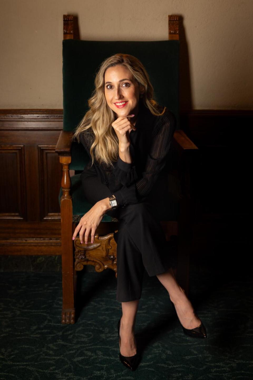 A woman sitting in a chair and leaning into her hand.