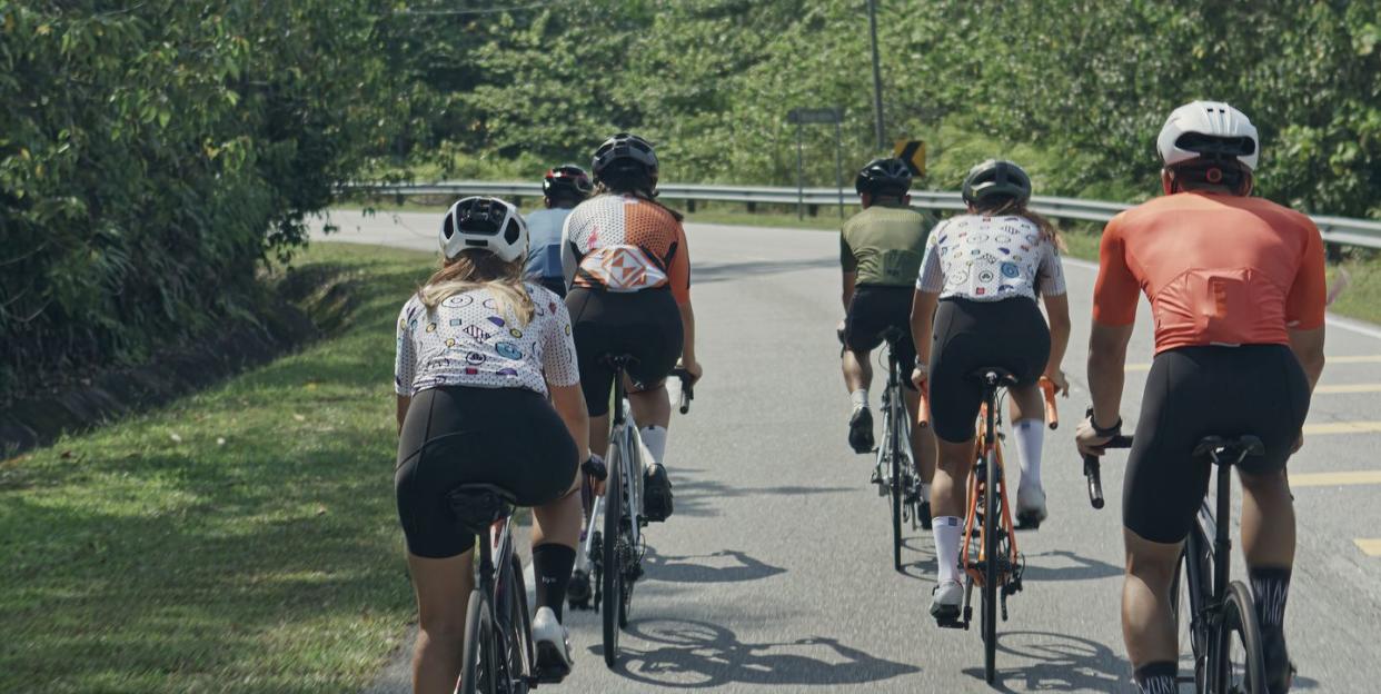 rear view asian chinese cyclist leader leading team cycling in rural area during weekend morning