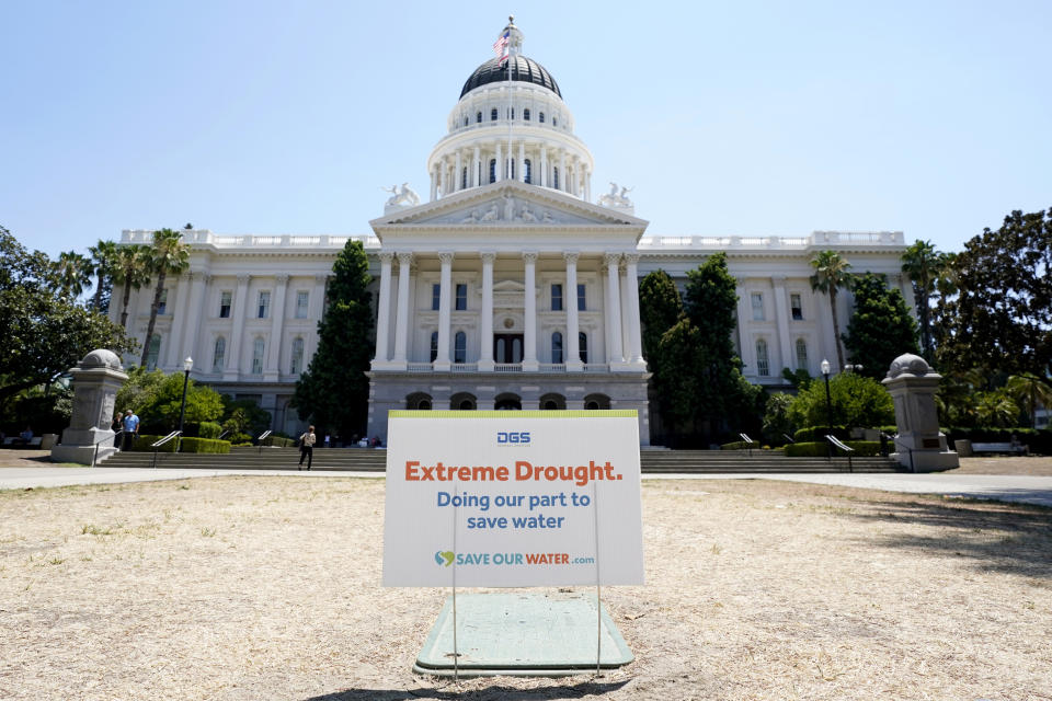 FILE - A sign about saving water is posted on browning grass outside the state Capitol in Sacramento, Calif., on Monday, July 11, 2022. California began its new water year on Oct. 1, 2022, and state officials are expecting another dry winter ahead. (AP Photo/Rich Pedroncelli, File)