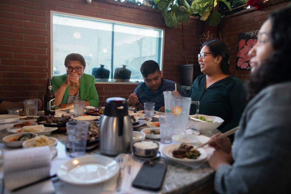 Four sit around a big table full of food in a restaurant.