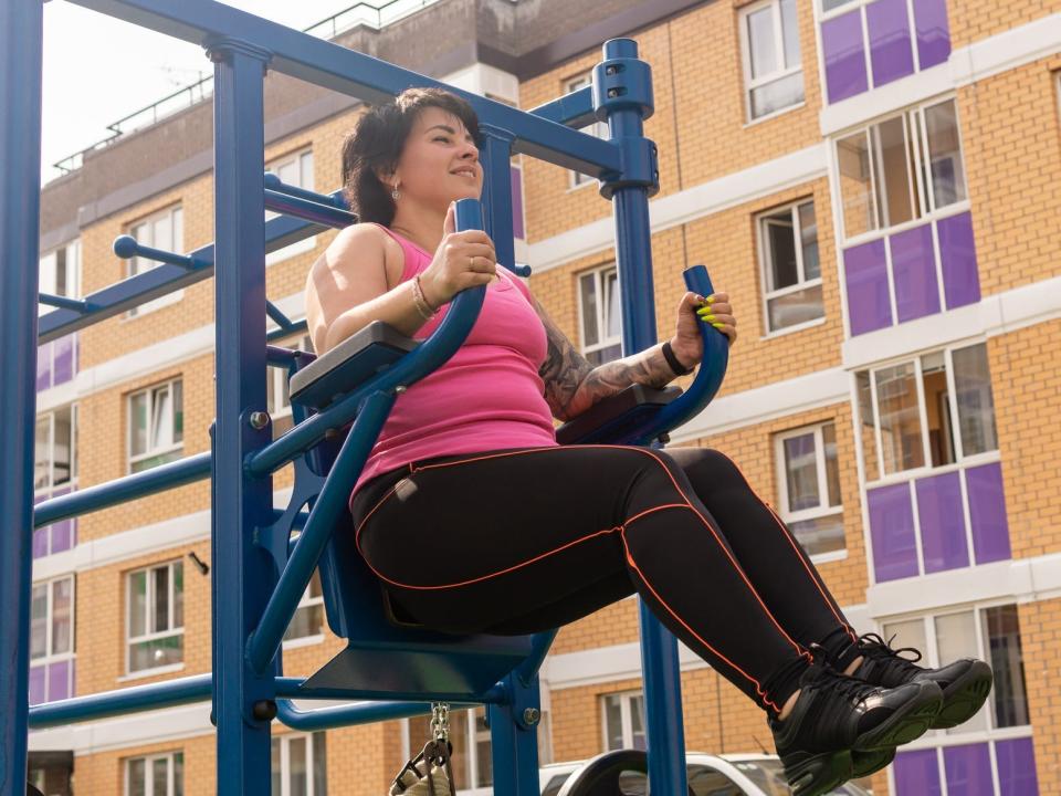 A woman doing a hanging leg raise exercises in an outdoor gym