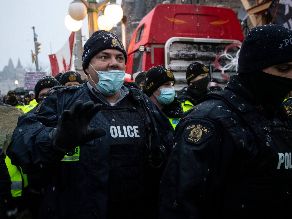 An RCMP officer asks people to back up as police make an arrest on Wellington Street on the 21st day of a massive protest against COVID-19 measures in Ottawa on Thursday, Feb. 17, 2022. (Justin Tang/The Canadian Press - image credit)