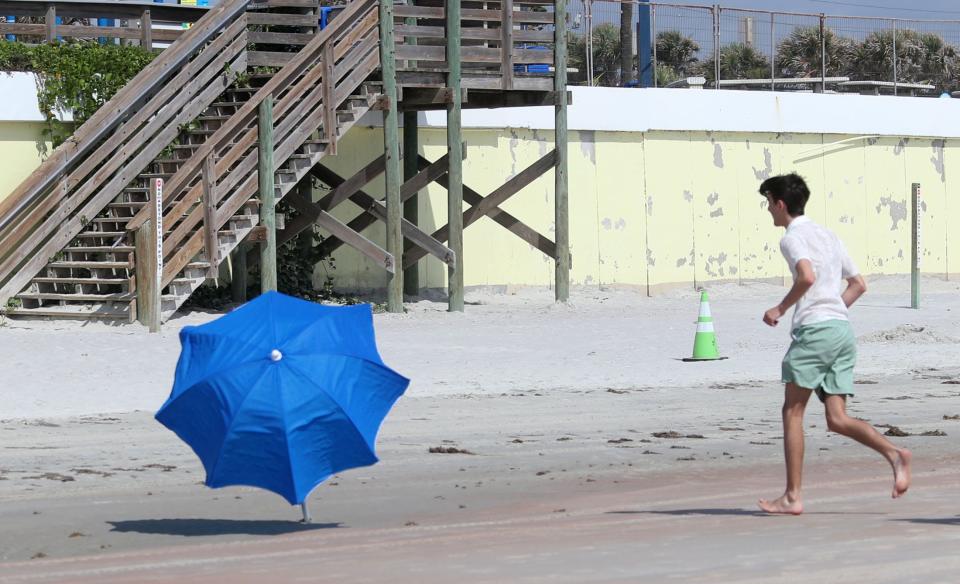 A beachgoer chases after a umbrella as a strong seabreeze, pushes it across the beach, Tuesday June 18, 2024 in front of Sun Splash Park in Daytona Beach. More extreme heat is expected this week in Volusia and Flagler counties, according to the National Weather Service in Melbourne.