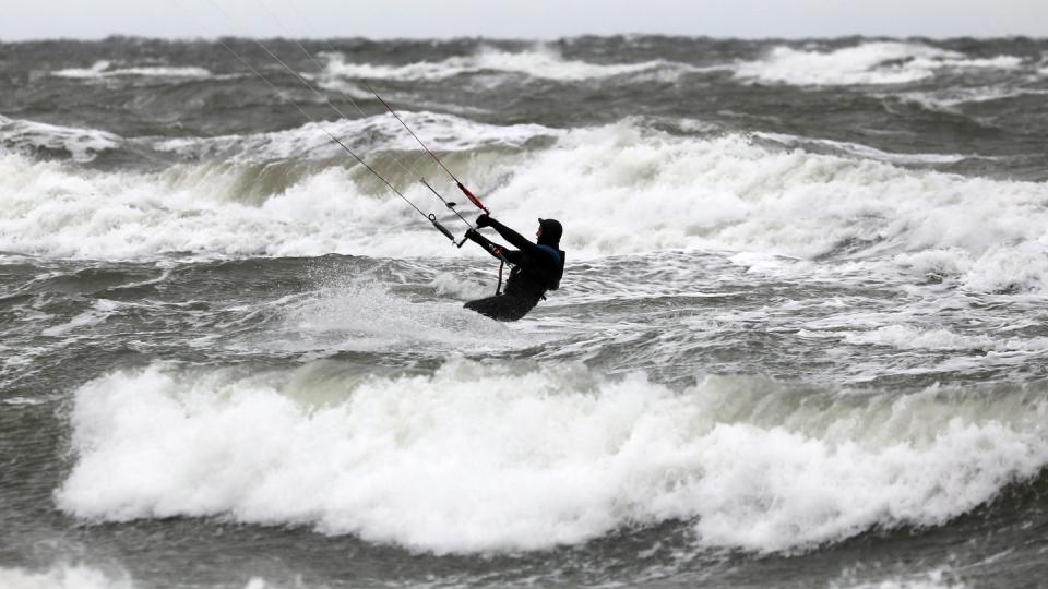 Ein Kite-Surfer nutzt den stürmischen Wind über der aufgewühlten Ostsee in Warnemünde.