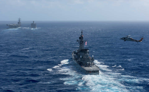 A U.S. MH-60S Sea Hawk flies by Japan's Maritime Self-Defense Force ship JS Shimakaze as it steams behind the Navy's forward-deployed aircraft carrier, USS Ronald Reagan - Credit: Reuters