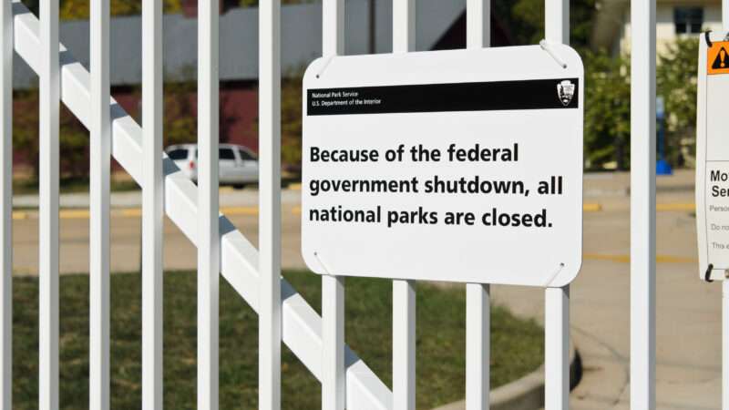 A sign on a gate that says "Because of the federal government shutdown, all national parks are closed."