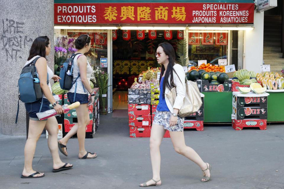 FILE - Tourists at left, walk front of a shop at the Chinese quarter in the 13th district of Paris, the largest Chinatown in Europe, Monday, July 8, 2013. The Little India and African markets near the Gare du Nord or the Chinatowns around the 13th arrondissement's Avenue de Choisy and Belleville metro station in Paris' east are all packed on Sundays. (AP Photo/Francois Mori)