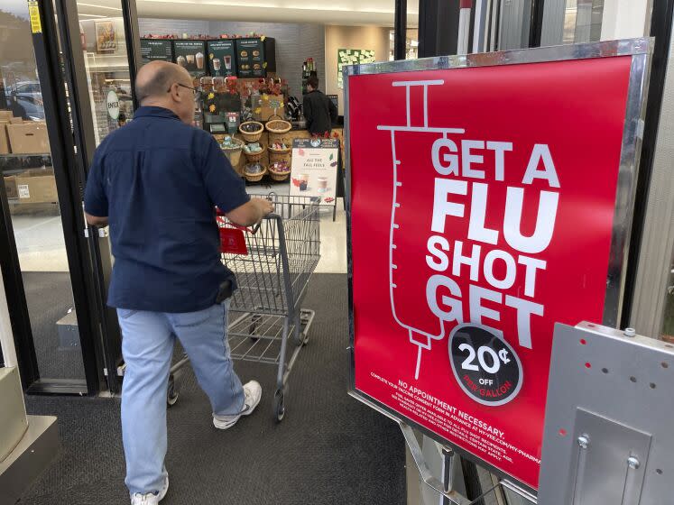 A shopper passes a sign urging people to get a flu shot outside a Hy-Vee grocery store in Sioux City, Iowa.