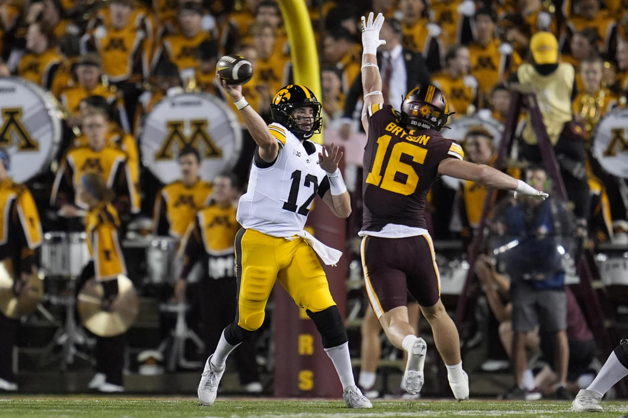 Iowa quarterback Cade McNamara (12) passes while pressured by Minnesota defensive back Coleman Bryson (16) during the first half of an NCAA college football game Saturday, Sept. 21, 2024, in Minneapolis. (AP Photo/Abbie Parr)