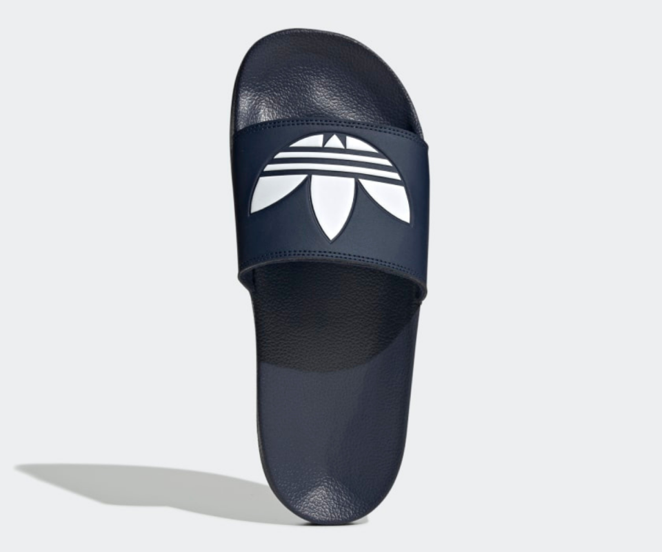 A navy pair of Adidas slides with the white logo on the front on a white background.