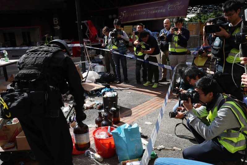 Members of a safety team established by police and local authorities look at items, next to the media, at the Hong Kong Polytechnic University (PolyU) in Hong Kong, China