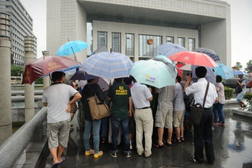 Unos periodistas se concentran ante el tribunal de la ciudad china de Hefei donde este jueves 9 de agosto comenzó el juicio contra Gu Kailai, la esposa del ex dirigente Bo Xilai, por homicidio. (AFP | Peter Parks)