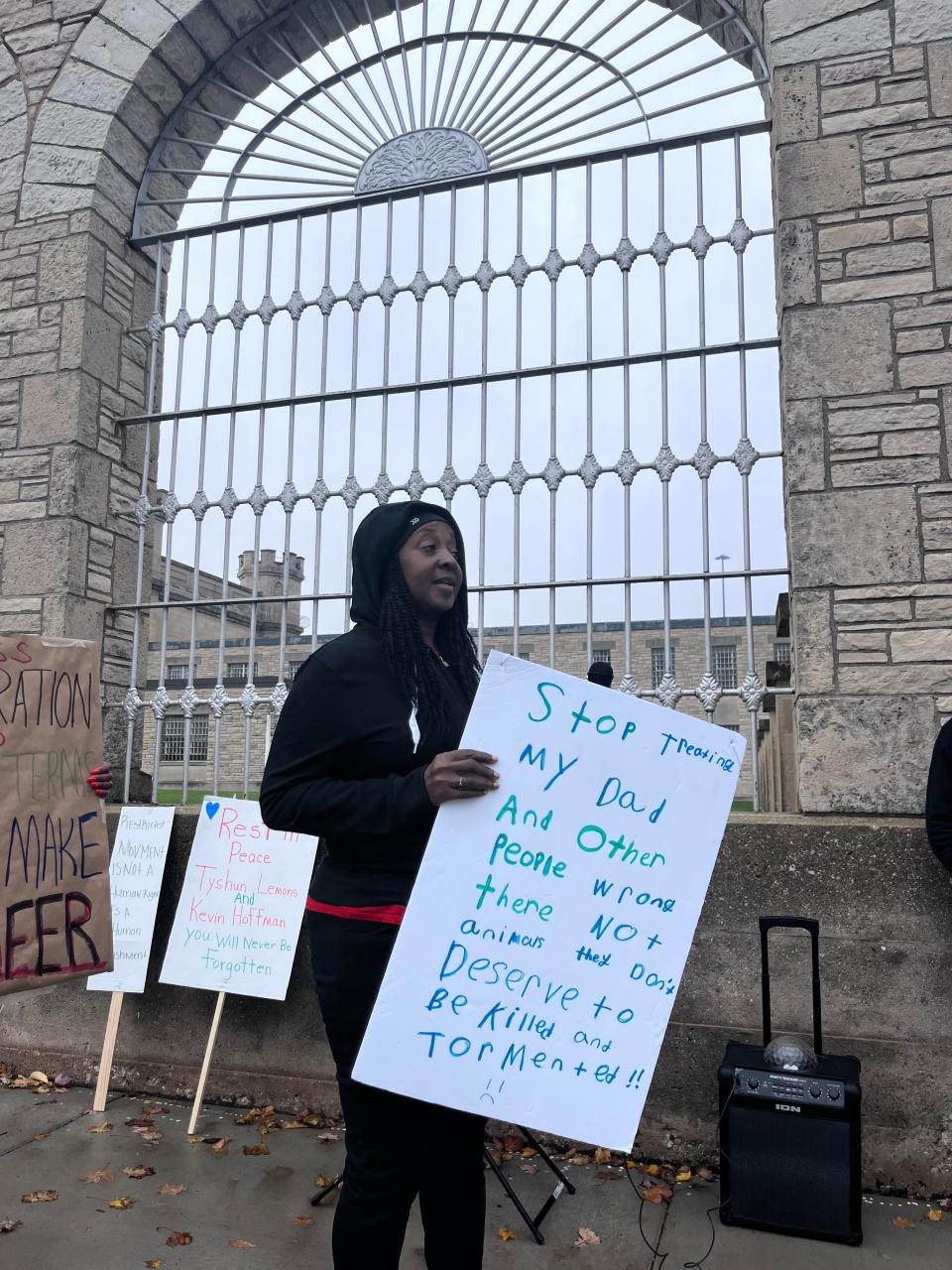 Carolyn Hayes speaks outside of Waupun Correctional Institution in Waupun on Wednesday, holding a sign made by her granddaughter for her son, Jonathan.