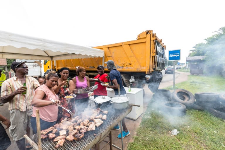 People eat at a barbecue at a road block in Cayenne, French Guiana, during a string of region-wide protests and road blockades