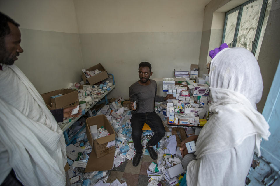 A pharmacist, center, speaks to patients as he sits among the packages of medicine able to be recovered in Hawzen, in the Tigray region of northern Ethiopia, on Friday, May 7, 2021. The hospital was damaged and looted by Eritrean soldiers who used it as a base, according to witnesses. (AP Photo/Ben Curtis)