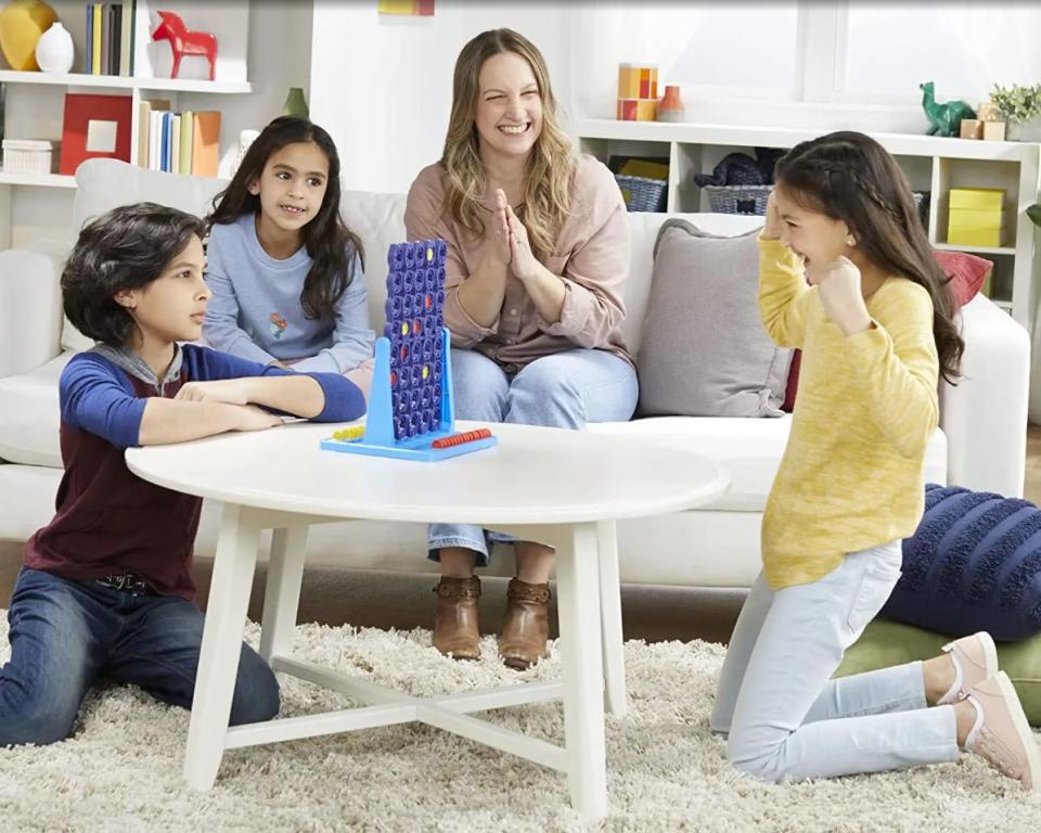 group of kids and family playing connect four game in living room