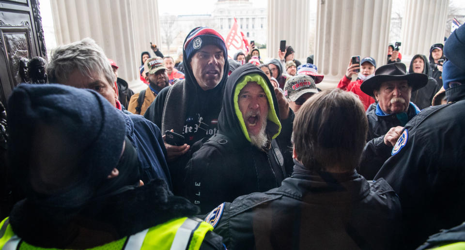 Trump supporters at the entrance of the US Capitol as police stand in front of them.