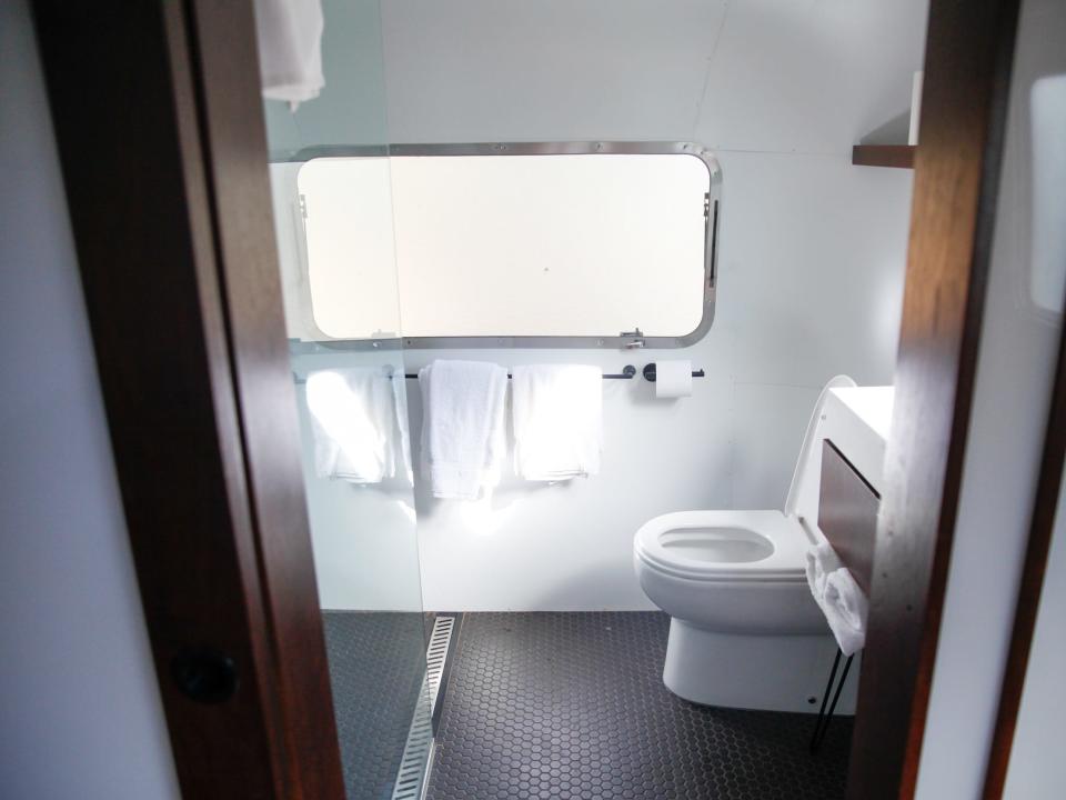 a toilet next to a window and shower