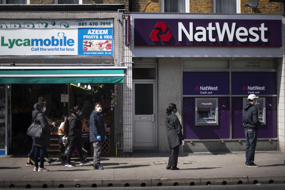 Shoppers wearing protective face masks stand 2m apart in a queue for a high street bank in East Ham, east London, as the UK continues in lockdown to help curb the spread of the coronavirus. (Photo by Victoria Jones/PA Images via Getty Images)