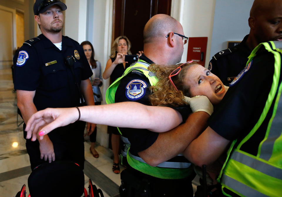 <p>Stephanie Woodward, of Rochester, NY, who has spina bifida and uses a wheelchair, is removed from a sit-in at Senate Majority Leader Mitch McConnell’s office as she and other disability rights advocates protest proposed funding caps to Medicaid, Thursday, June 22, 2017, on Capitol Hill in Washington. (Photo: Jacquelyn Martin/AP) </p>