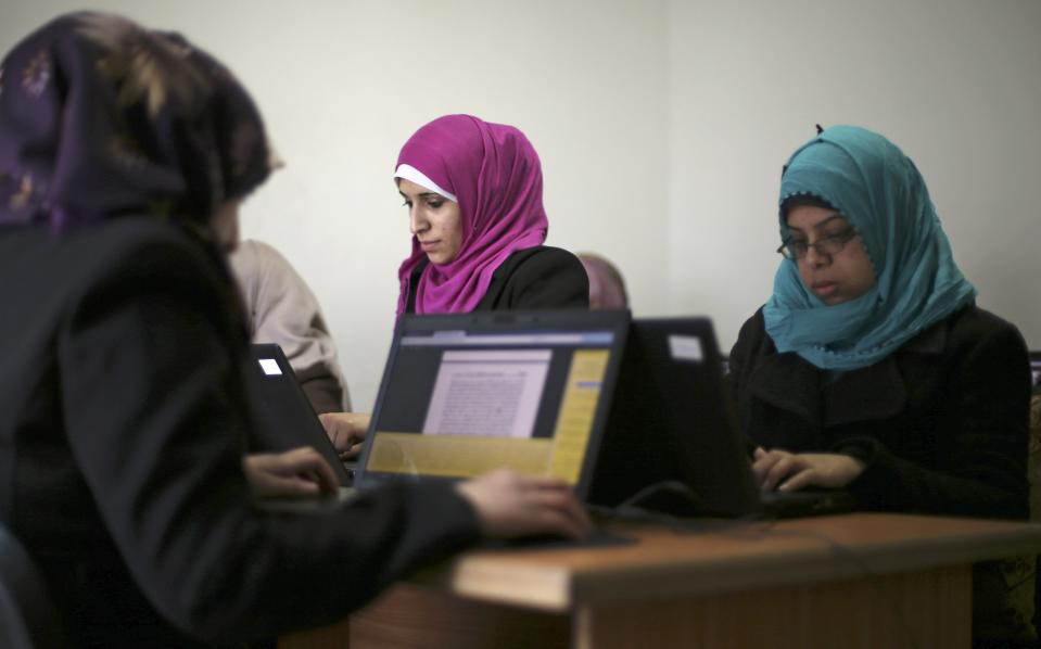 Palestinian employees process data on their laptops at Unit One in Gaza City January 15, 2015. In nine years, Gaza-based IT entrepreneur Saady Lozon and his partner Ahmed Abu Shaban have transformed their firm, Unit One, from a tiny outfit in a single room in the blockaded Gaza Strip into a successful business with clients in Europe, the United States and the Arab world. They can't leave Gaza easily, but they can develop applications for Web and mobile devices online and provide international clients with data-management services, competing with firms in India and elsewhere. Picture taken January 15, 2015. To match story MIDEAST-PALESTINIANS/TECHNOLOGY REUTERS/Mohammed Salem (GAZA - Tags: SCIENCE TECHNOLOGY BUSINESS)