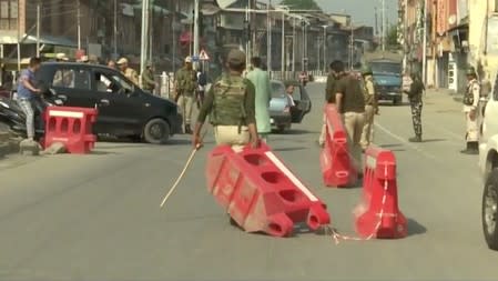 Policemen pull barricades on a street in Srinagar