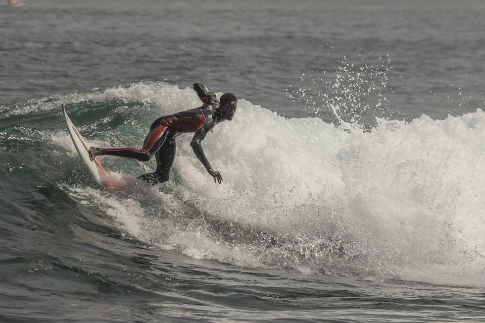 Cherif Fall, Senegal's number one surfer paddles to the wave in the Atlantic Ocean in Dakar, Senegal, Wednesday, Feb. 28, 2024. Instead of training in the waves off his Senegal homeland, Fall was wistfully preferring to be in Puerto Rico, where the last surfing qualifying competition for the Paris Olympics ends on Saturday. Senegal had nobody there to try and claim the last 14 spots for men and women because there was no money to send them, Fall says. (AP Photo/Sylvain Cherkaoui)