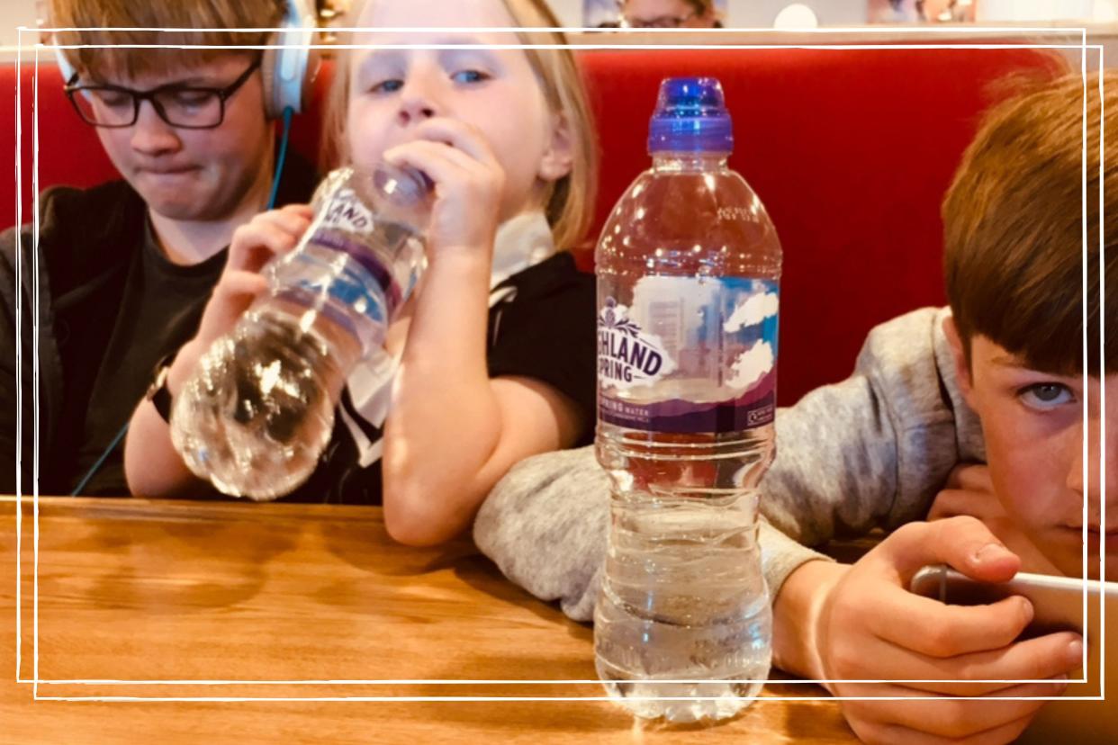  Three children using smartphones in an airport. 