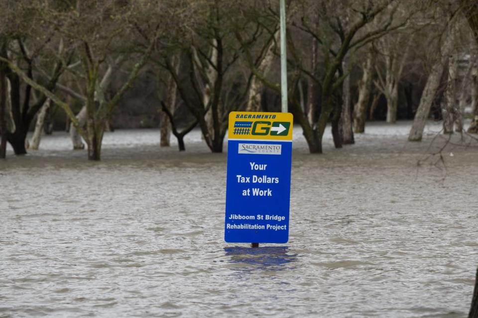 Floodwaters in Discovery Park nearly reach the bottom of a sign in the park, which is closed to the public, on Tuesday.