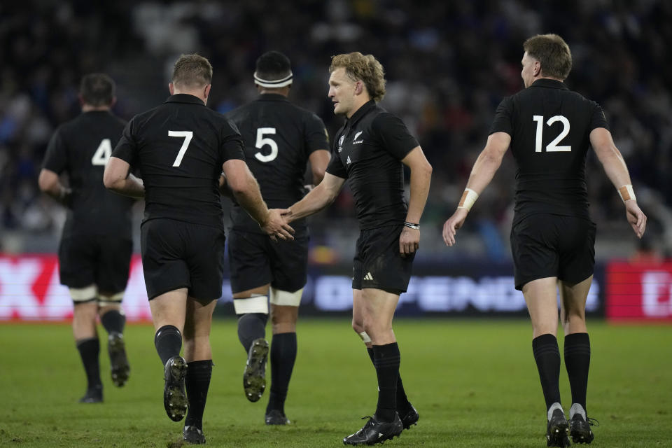 New Zealand's Damian McKenzie, centre, celebrates with captain Sam Cane after teammate Cam Roignard scored a try during the Rugby World Cup Pool A match between New Zealand and Uruguay at the OL Stadium, in Lyon, France Thursday, Oct. 5, 2023. (AP Photo/Pavel Golovkin)