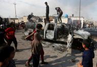 Protesters step on a military vehicle of Iraqi security forces after burning it, during ongoing anti-government protests in Basra