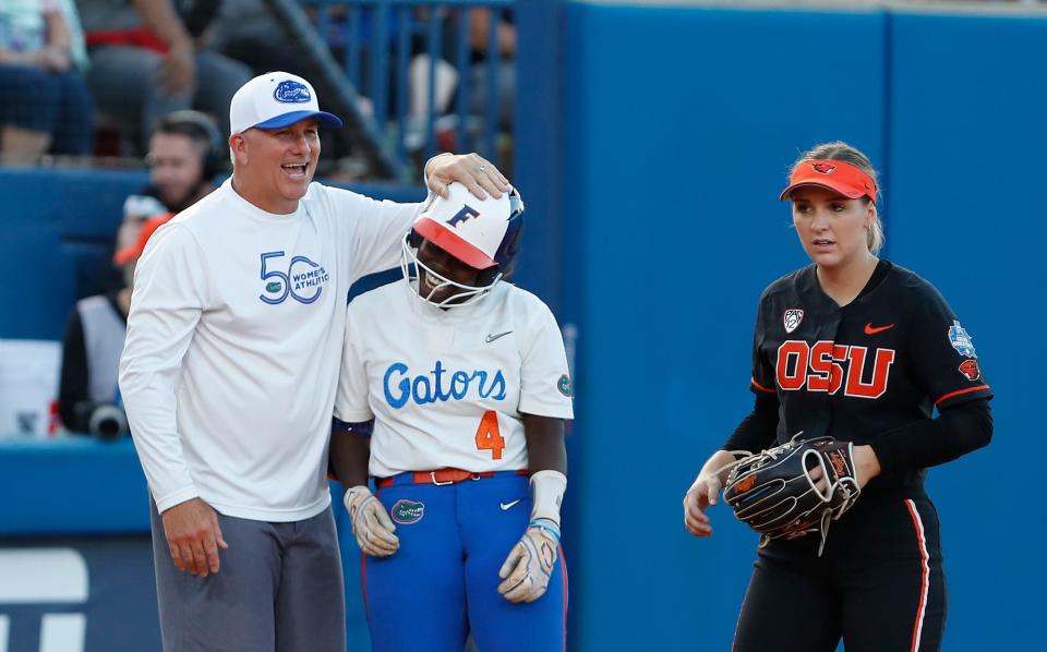 Florida coach Tim Walton and Charla Echols (4) celebrate after she reached third base during the fifth inning of an NCAA softball Women's College World Series game against Oregon State on Thursday, June 2, 2022, in Oklahoma City.