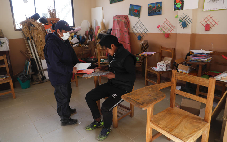 Instructor Marina Vasquez and student Jose Choque go over his homework at the local school in the Urus del Lago Poopo indigenous community, in Punaca, Bolivia, Monday, May 24, 2021. Aided by the government and a local foundation, community elders have invited teachers from a related branch of the Uru, to teach their native tongue — one of 36 officially recognized Bolivian languages — to their children. (AP Photo/Juan Karita)