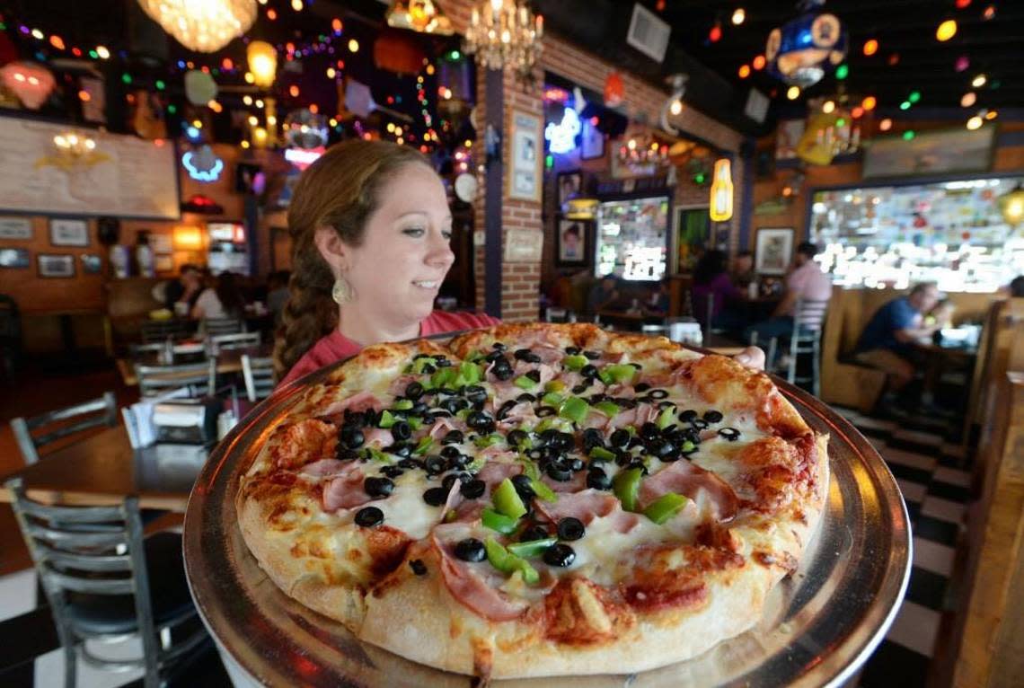Carrie Sullivan serves up a green pepper, black olive and ham pizza at Ingleside Village Pizza where they are celebrated their 25th anniversary in July in this Telegraph file photo.
