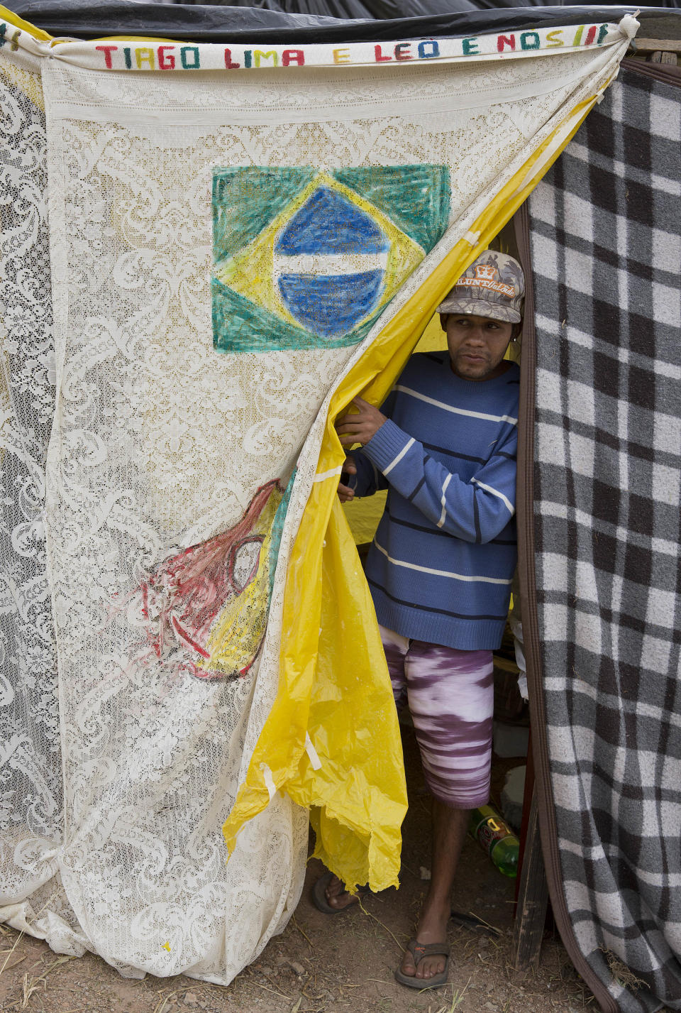 A man stands inside his shack which was built on occupied land, within view of Itaquerao stadium, in Sao Paulo, Brazil, Tuesday, May 6, 2014. Thousands of impoverished Brazilians have squatted near the stadium hosting the opening match of soccer’s biggest tournament, saying the arena’s construction is to blame for rent increases that drove them out of their homes. (AP Photo/Andre Penner)