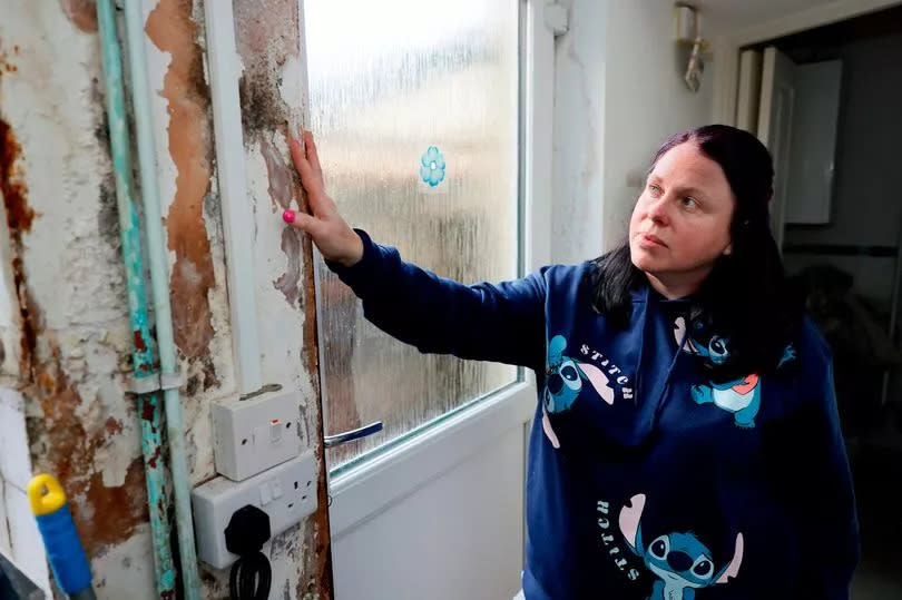 Woman in kitchen looking at damp wall