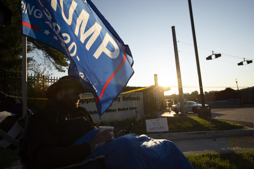 President Donald Trump supporter Richard Potcner, drinks a coffee at the main gate of Walter Reed National Military Medical Center in Bethesda, Md., Saturday morning, Oct. 3, 2020. Stricken by COVID-19, Trump was flown to Walter Reed on Friday night. (AP Photo/Jose Luis Magana)