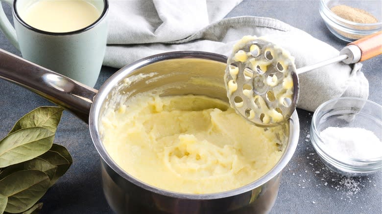 Pot of mashed potatoes with masher