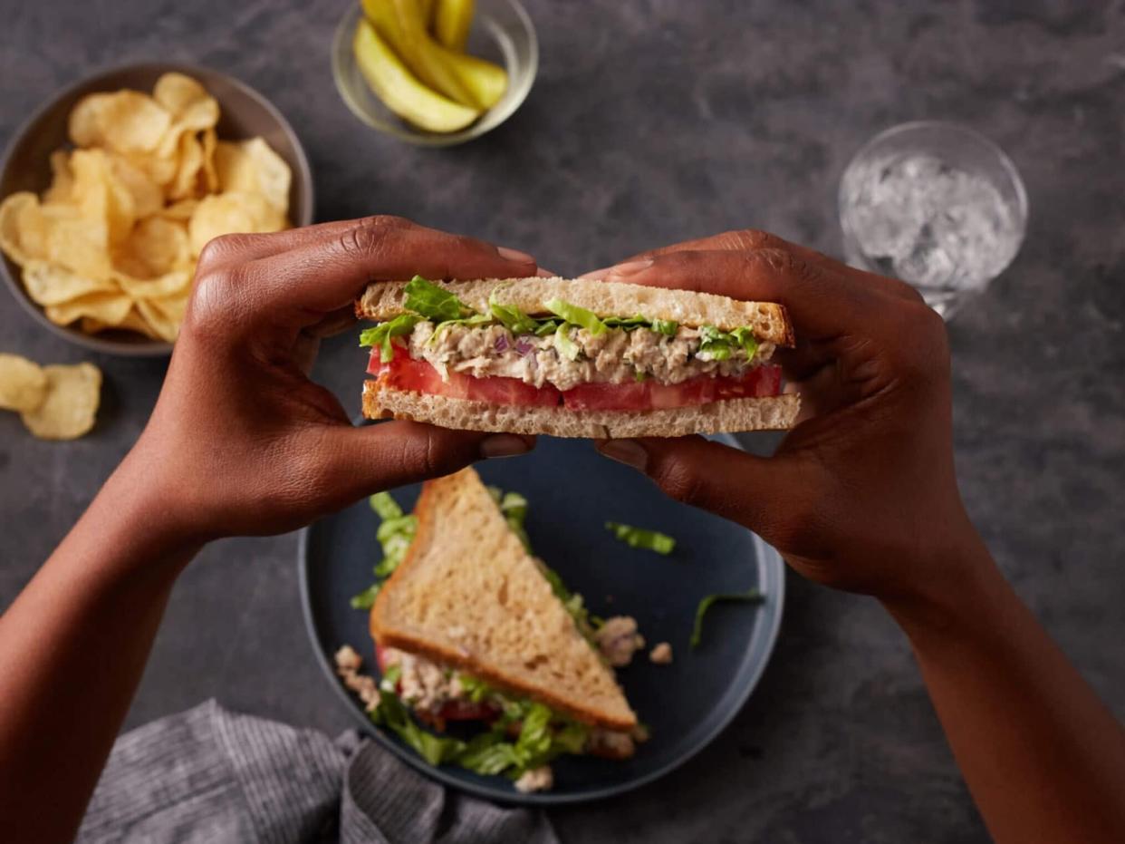 person holding vegan tuna sandwich