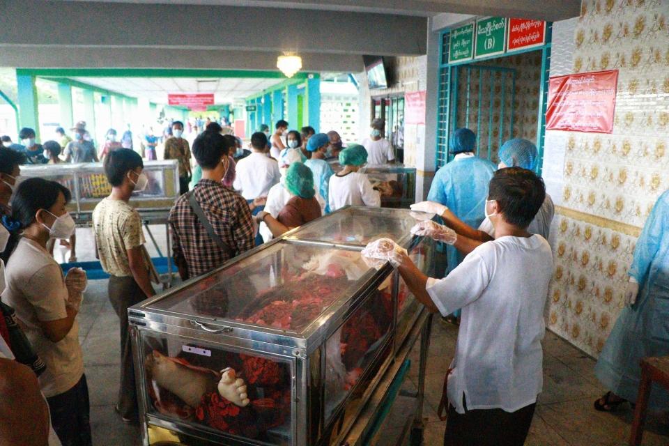 People wearing face masks wait while caskets with bodies are queued outside a crematorium at the Yay Way cemetery in Yangon, Myanmar, Wednesday July 14, 2021. The number of people dying in Myanmar's biggest city, Yangon, which is facing a coronavirus surge and a shortage of oxygen to treat patients, has been climbing so quickly that charity groups said Wednesday they are almost overwhelmed. (AP Photo)