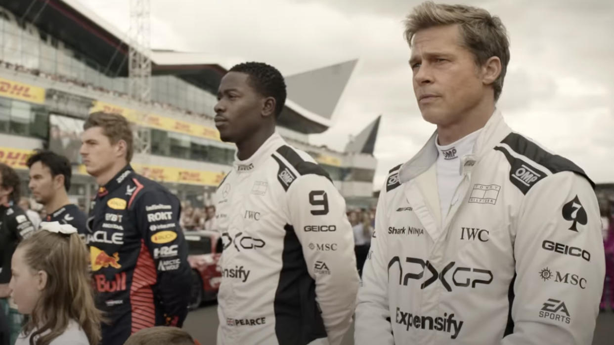  Sonny Hayes (Brad Pitt) and Joshua Pearce stand on a track with others in F1. 