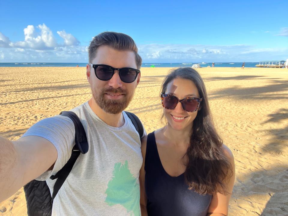 A man and a woman take a selfie on a beach.