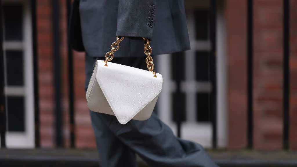 a woman at london fashion week with a leather bag with a chain strap to illustrate a guide to the best chain bags of 2023